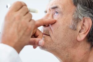 Doctor checking older man's eyes.