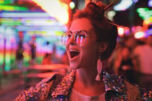 Woman wearing sparkling jacket on the city street with neon lights