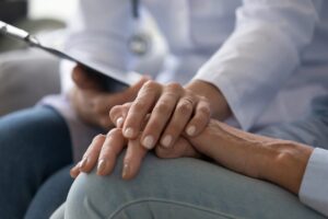 Young woman doctor holding hand of senior grandmother patient, closeup