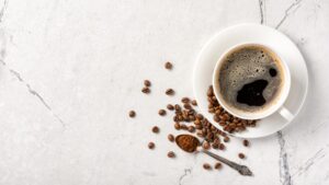 A cup of coffee with coffee beans around it. One example of a legal stimulant.