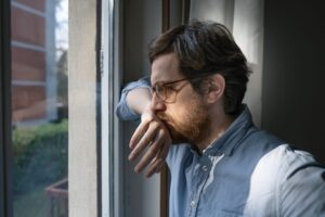 Thoughtful anxious guy looking out the window