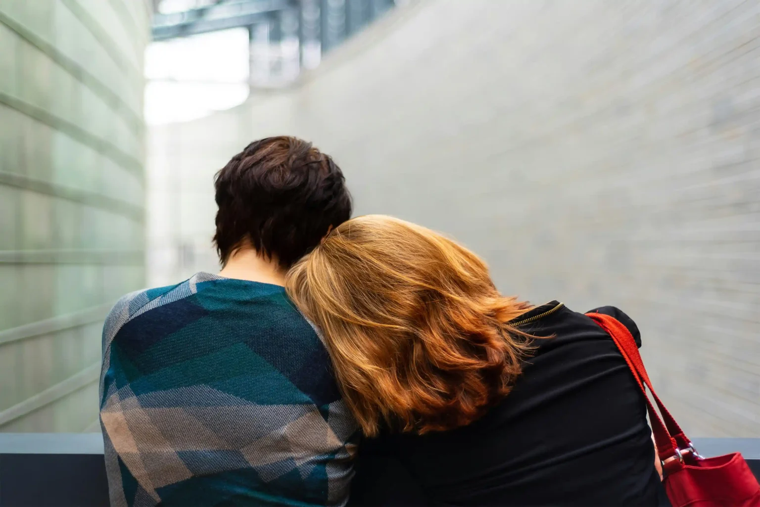 Back of people with one resting her head on the shoulder of the other