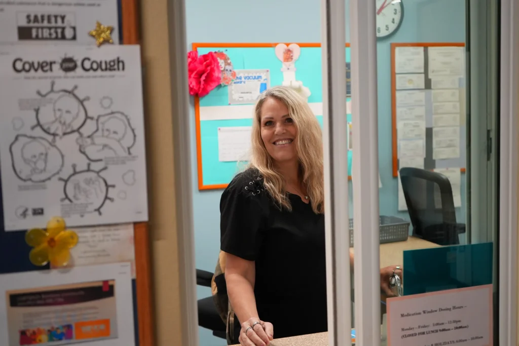 Woman peering through an open receptionist window