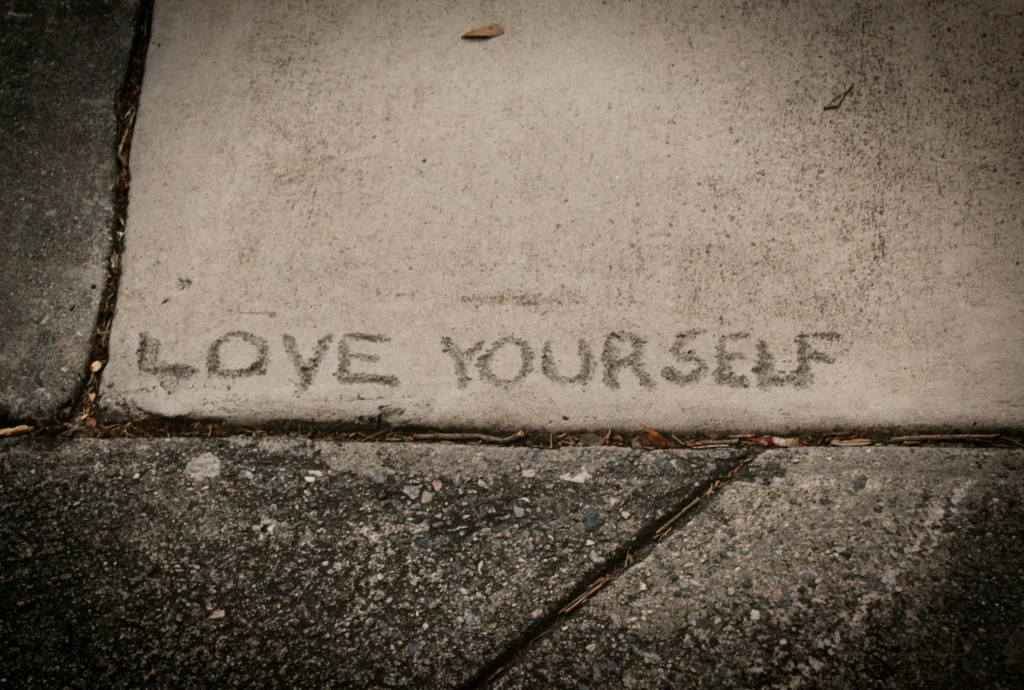 image of the words "love yourself" carved into a sidewalk