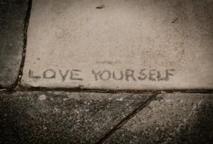 image of the words "love yourself" carved into a sidewalk