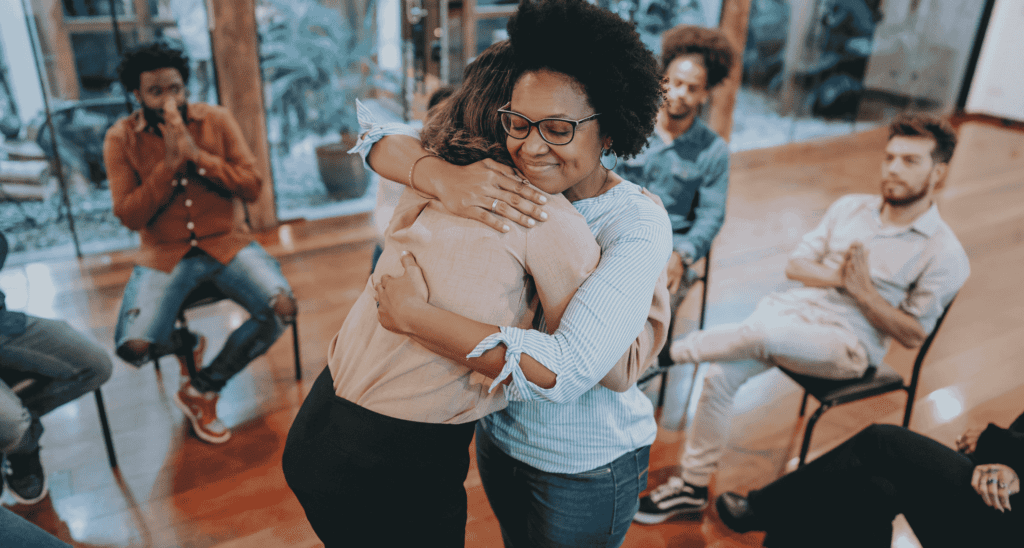 Two people hugging in a group setting