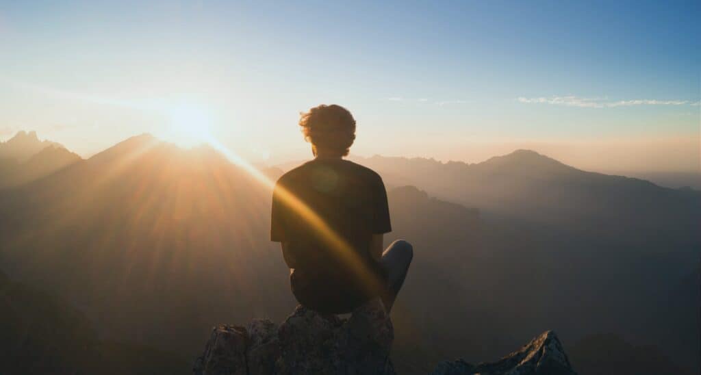Man sitting at the top of a mountain
