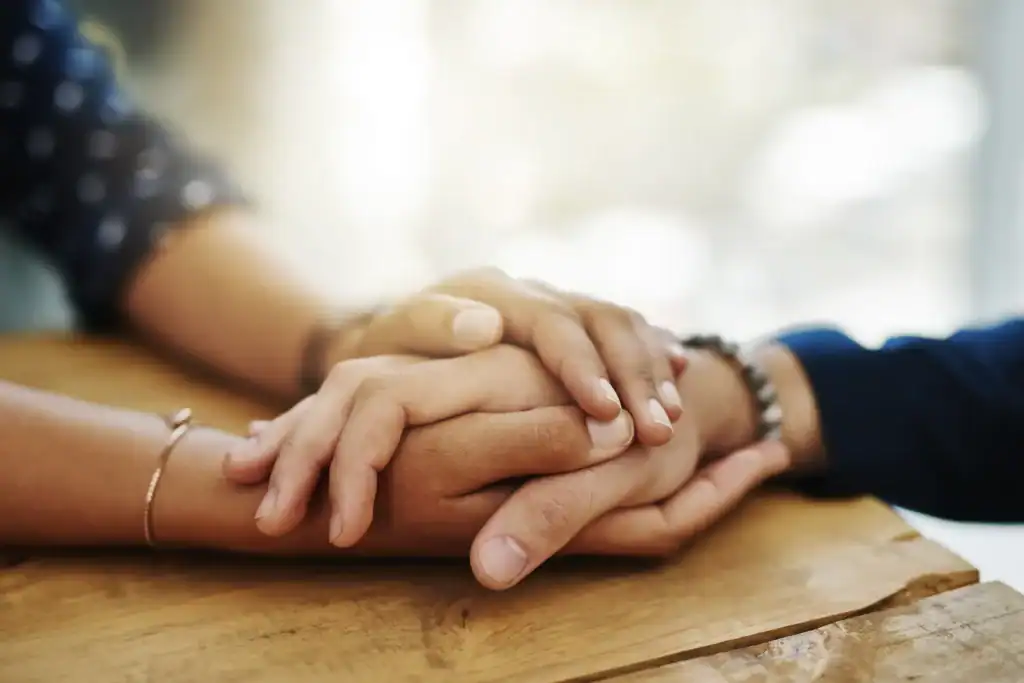 two people holding hands on table