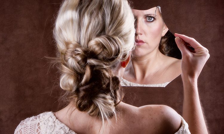 woman looking into a broken mirror