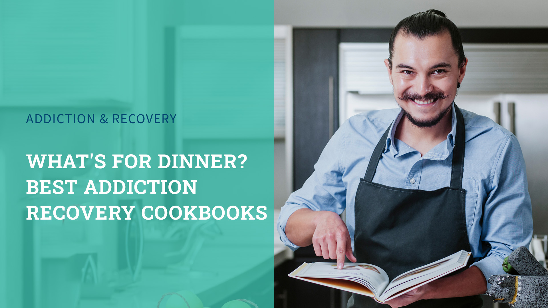 Man in a kitchen holding a cookbook looking at the camera